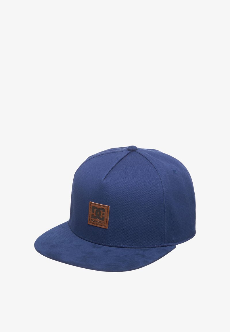 Navy blue baseball cap made from fabric with a flat brim. Features a brown leather logo patch on the front and a textured finish.