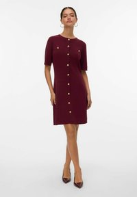 Abito bordeaux fino al ginocchio con maniche corte, caratterizzato da dettagli con bottoni dorati e un design a maglia testurizzata, completato da un colletto tondo.