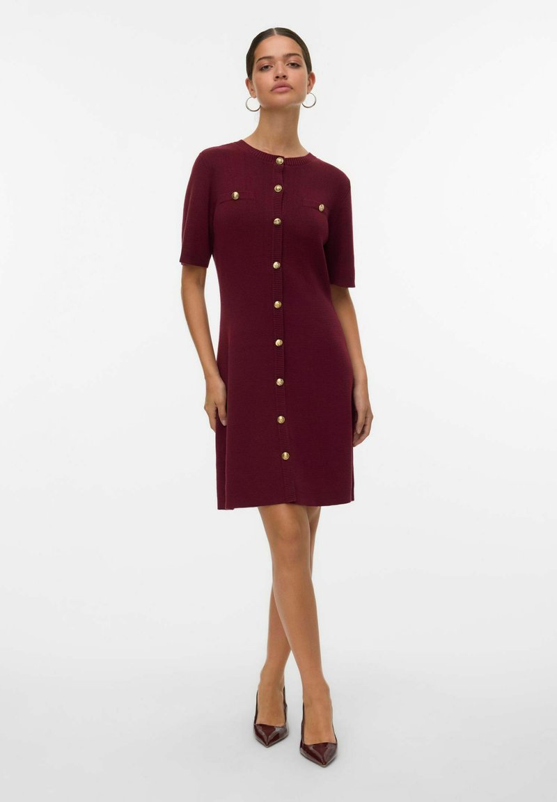 Abito bordeaux fino al ginocchio con maniche corte, caratterizzato da dettagli con bottoni dorati e un design a maglia testurizzata, completato da un colletto tondo.