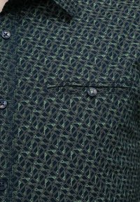Korte mouw overhemden in donkerblauwe stof met een geometrisch groen patroon, voorzien van een knoopsluiting op de borstzak en een puntige kraag.