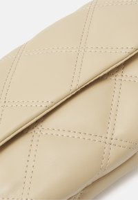 Clutch trapuntata beige realizzata in pelle sintetica, con un motivo a diamante e cuciture a contrasto. Texture liscia con un design piegato.