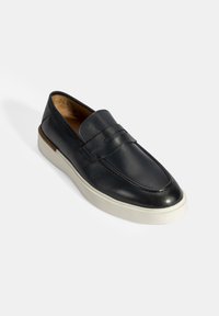 Zwarte leren instappers met een gladde afwerking, voorzien van een gestikte design, rubberen zool en een crèmekleurig plateau voor contrast.