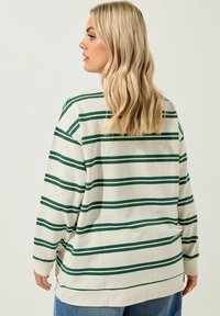 Langarm-Pullover mit Rundhalsausschnitt in Off-White mit grünen horizontalen Streifen. Weiche Textur, entspannte Passform und gerippte Bündchen.