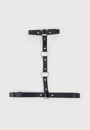 Mustast väärisnahast valjaheide, millel on hõbedased metallist rõngad ja naelad, reguleeritavate rihmadega, mis on paigutatud vertikaalis ja horisontaalis.