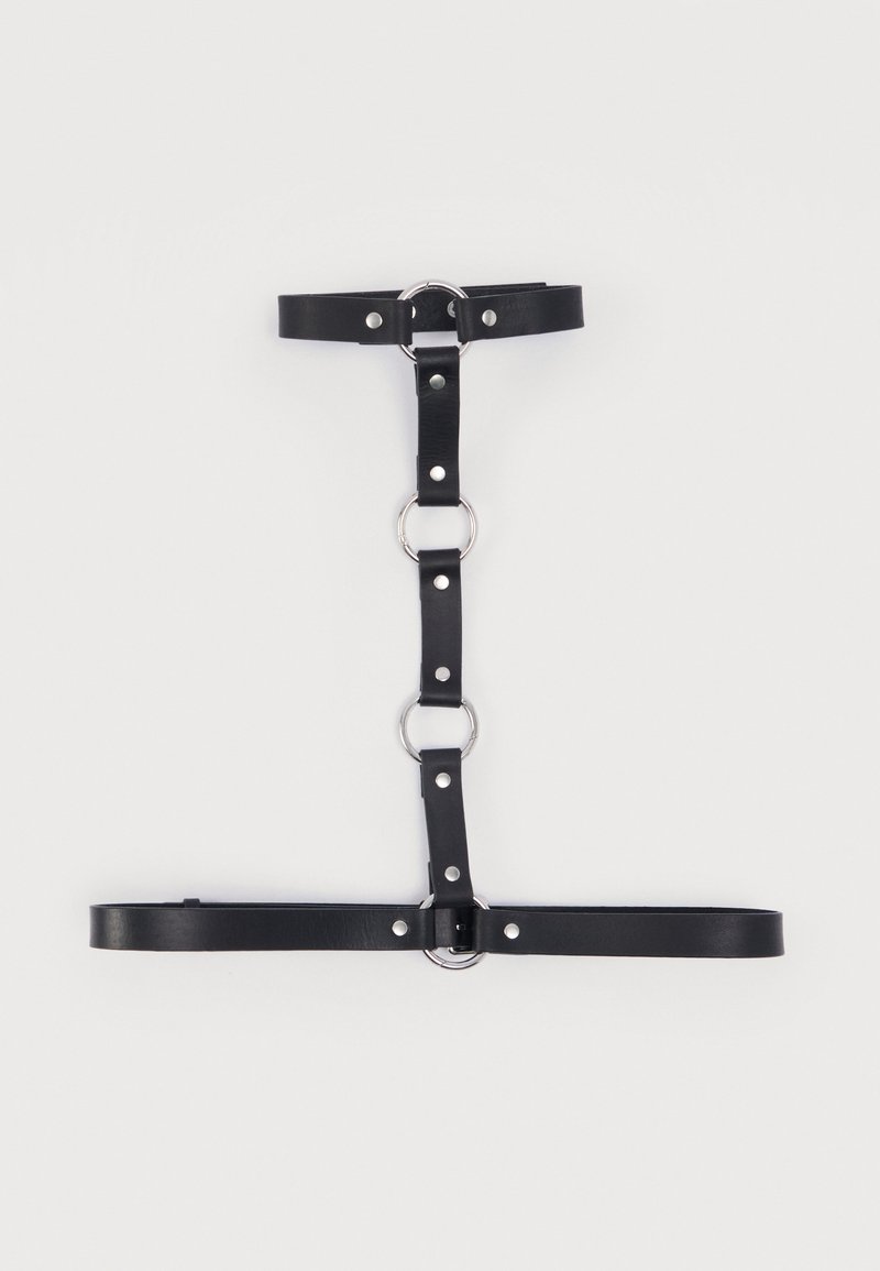 Μαύρο ζωνάκι από τεχνητό δέρμα με ασημένιους μεταλλικούς κρίκους και τρουκς, με ρυθμιζόμενους ιμάντες οργανωμένους σε κάθετη και οριζόντια διάταξη.