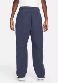 Pantaloni della tuta blu navy con vestibilità rilassata, vita elastica e polsini affusolati. Realizzati in tessuto morbido con cuciture sottili e senza loghi visibili.