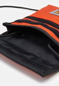 Borsa di stoffa arancione con accenti neri, dotata di un rivestimento interno nero liscio e di un cordino per la chiusura. Presenta una superficie testurizzata e cuciture.