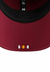 Bordeauxfarbene Mütze mit schwarzem Innenfutter, die auf der Rückseite ein kleines Design aus vier farbigen Blöcken (weiß, pink, gelb, rot) aufweist.