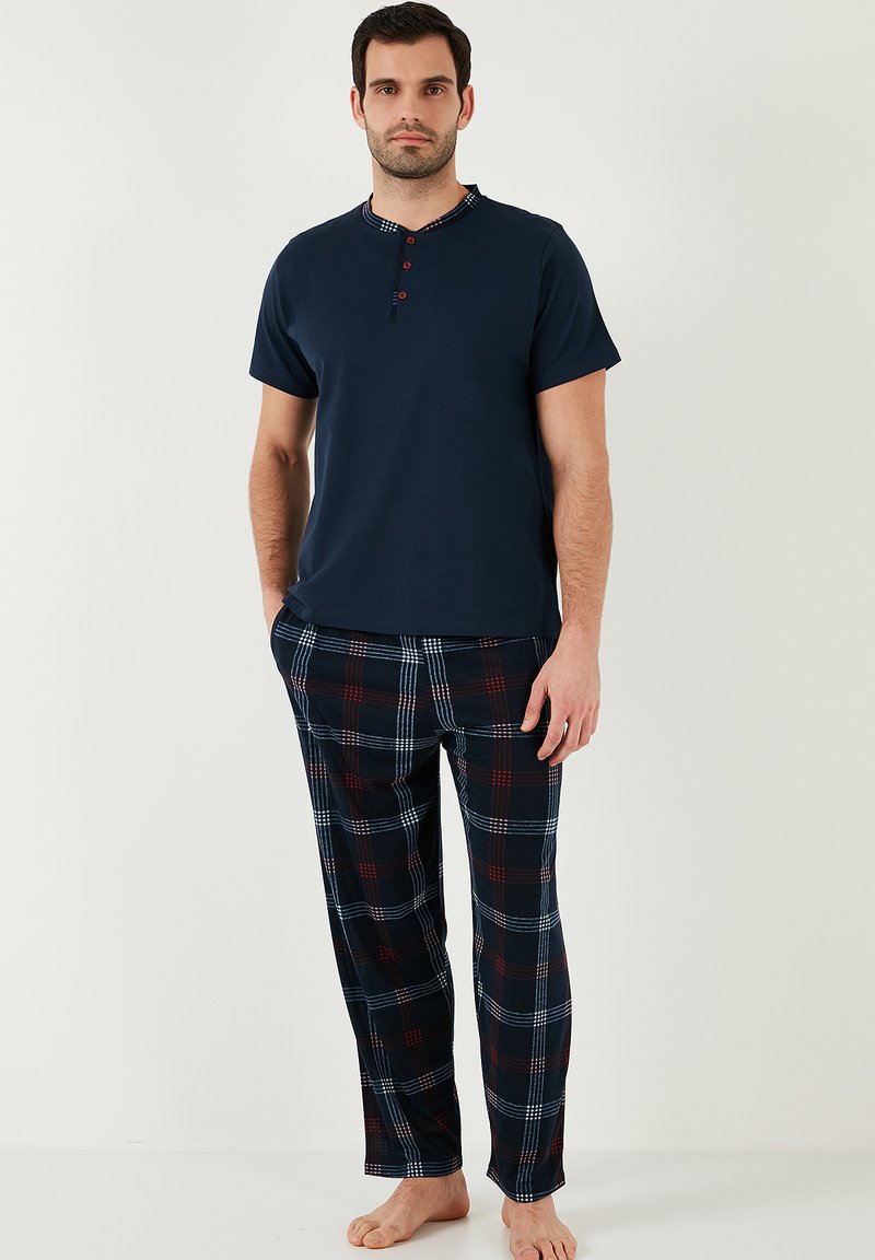Cămașă navy cu mâneci scurte, cu guler în carouri și trei nasturi roșii; pantaloni de pijama în carouri, în culorile navy, roșu și alb, dintr-un material moale.