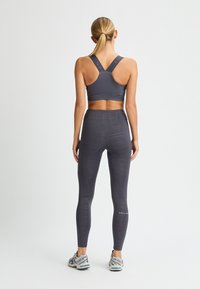 Sujetador gris deportivo y leggings con patrones geométricos. Diseño elegante, material elástico. Calzado atlético completa el atuendo.