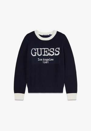 Pull en tricot bleu marine avec accents côtelés blancs et col rond. Présente l'inscription "GUESS Los Angeles 1981" en lettres blanches audacieuses sur le devant.