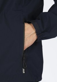 Navy wasserfeste Jacke mit einem Reißverschluss-Seitentasche und verstellbarem Bündchen. Ausgestattet mit elastischen Bindungen und einem Logo-Tag am Saum. Glatte Textur.