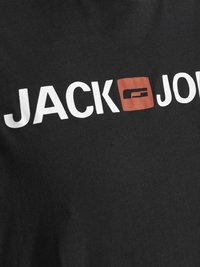 Mustapaita, jossa on valkoiset tekstit "JACK" ja "JONES" ja punainen neliölogo niiden välissä. Sileä pinta, rento muotoilu.