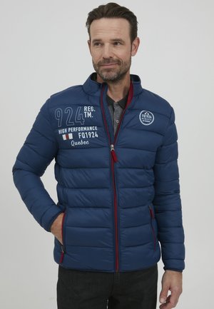 Plavi puffer jakna sa kvadriranim teksturom, crvenim detaljima na zipu i tiskanim grafikom. Ovratnik koji se podiže, bočne džepove i prilagođen dizajn.