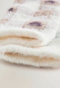 Mi�ękki, wełniany szalik w kolorze kremowym, o delikatnej fakturze, z brązowymi i szarymi cętkowanymi wzorami. Krawędź jest starannie podwinięta i lekko postrzępiona.