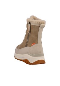 Botas impermeables en color beige con forro de pelo, cremallera lateral y suela de goma gruesa. El diseño presenta paneles lisos y texturizados.