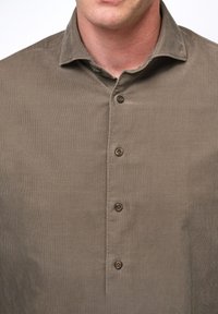 Oliwkowa, sztruksowa koszula zapinana na guziki z kołnierzykiem i czterema brązowymi guzikami, z pionowym, prążkowanym wzorem.