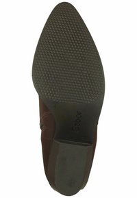 Suela de zapato de cuero marrón con agarre de goma texturizada, diseño de punta afilada y marca en relieve. Presenta una textura de tacón contrastante.