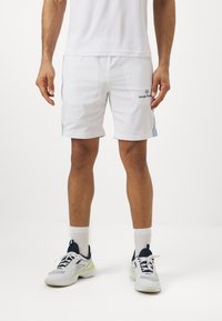 Witte sportshorts met lichtblauwe accenten, met een logo aan de rechterkant. Gecombineerd met bijpassende witte sokken en sneakers.