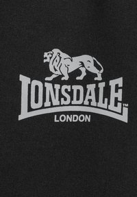 Mustapohjainen tekstiili vaaleanharmaalla logolla, jossa on leijona ja teksti "Lonsdale London" paksulla fontilla, tasaisella taustalla.