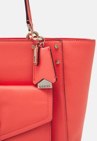 Borsa tote in pelle corallo con finitura texturizzata, hardware in argento e etichetta con logo. Presenta una tasca frontale e cuciture a contrasto.