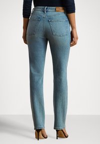 Gaiši zilas džinsa bikses ar augstu jostasvietu, taisnas kājas dizainu, divas aizmugures kabatas un teksturētu audumu. Brūns ādas ielāps pie jostasvietas.