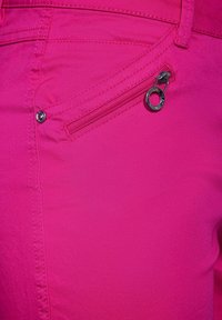 Różowe na gorąco spodnie z boczną kieszenią na zamek z srebrnym metalowym akcentem, gładką teksturą i widocznym przeszyciem na szwach.