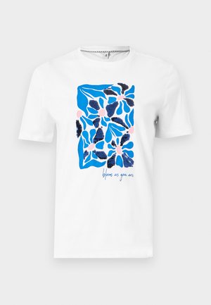 Chemise blanche à manches courtes avec un motif floral abstrait bleu et rose et des sequins bleu marine, texte "épanouis-toi tel que tu es" en bas à droite.