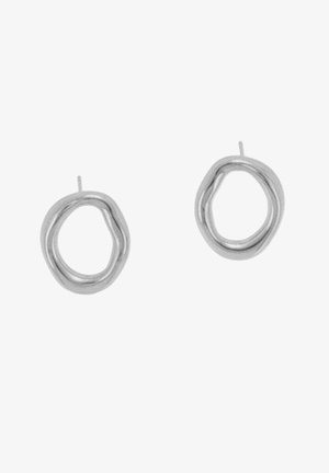 Srebrne metalowe kolczyki o abstrakcyjnym, płynnym kształcie z dwoma zazębiającymi się pętlami. Gładka faktura z błyszczącym wykończeniem.