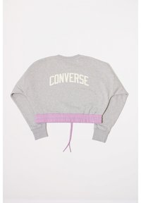Sudadera gris recortada con cintura elástica morada y cordón, que presenta el texto blanco "CONVERSE" en la parte posterior. Textura suave.