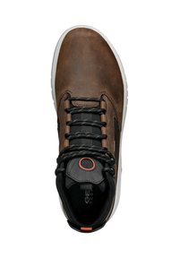 Zapato de cuero marrón con lengua de malla negra, cordones negros y suela de goma. Presenta un acento naranja cerca del ojal y marca en la plantilla interna.