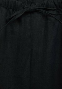 Black linen pants with a drawstring waist. The fabric texture is smooth and slightly matte, showcasing a consistent dark color.