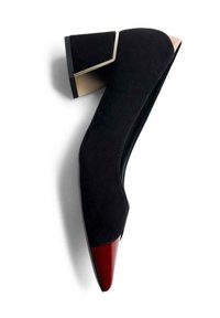 Zapato de tacón alto de ante negro con un diseño geométrico, que presenta una puntera puntiaguda roja brillante y un acento beige en el tacón.