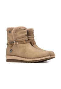 Botines tan con forro de piel sintética, exterior de cuero, correas decorativas con acentos metálicos y suela de goma texturizada.