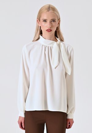 Weißes Blusenshirt mit hohem Kragen, gerafften Details und einer gebundenen Schleifenakzent. Lange Ärmel mit Knopfmanschetten; glattes, leichtes Gewebe.