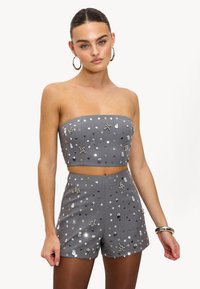 Ensemble gris en deux pièces comprenant un crop top bustier et un short taille haute, orné de sequins réfléchissants et d'embellissements floraux.