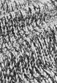 Strickstoff mit einer strukturierten Mischung aus dunklen und hellen Grautönen, der eine gemütliche und warme Erscheinung mit einem dicken, verwobenen Muster schafft.