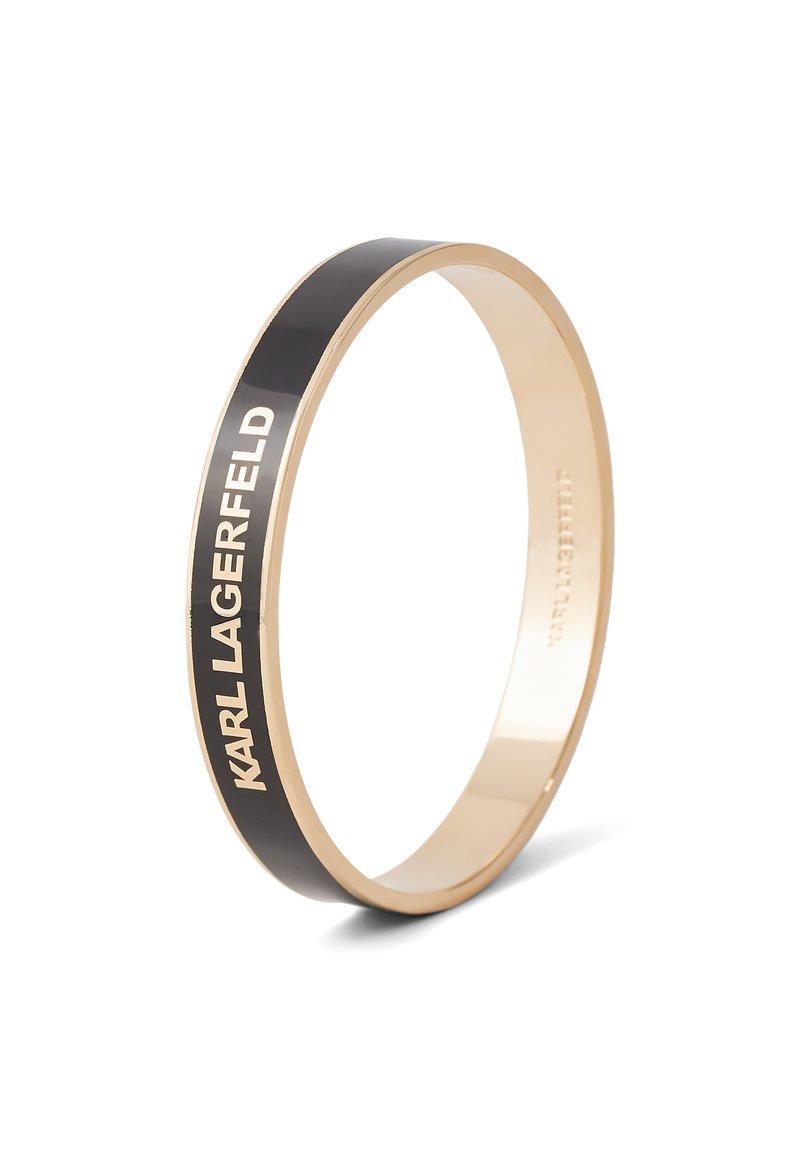 Bracelet jonc doré avec un inlay en émail noir. Présente "KARL LAGERFELD" gravé sur l'extérieur. Surface lisse et design épuré.