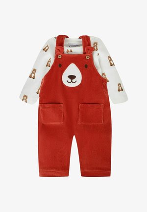 Raudonos korduro kronšteino kombinezonas kūdikiui su meškos veidu ant krūtinės, derinamas su balta ilgomis rankovėmis marškinėliais su rudos meškos atspaudu.