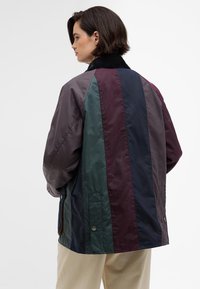 Színezett szélvédő, függőleges csíkokkal sötétzöld, bordó, tengerészkék és szürke színekben. Könnyű, texturált anyagból készült, kordbársony gallérral.