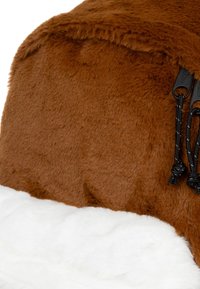 Tessuto in pelliccia sintetica marrone con un soffice retro bianco; presenta dettagli con cordini neri e una superficie texture.