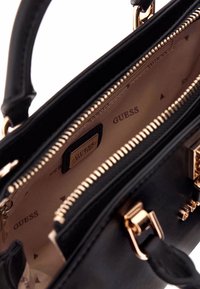 Borsa a tracolla nera in pelle con finiture dorate, dotata di apertura con zip e interno foderato che presenta un motivo a triangolo ripetuto.