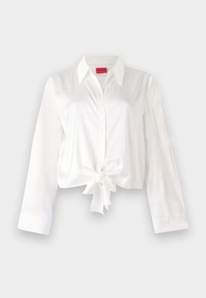 Gekürzte, langärmlige Bluse aus weißem Satinmaterial, mit einer vorderen Bindung und klassischem Kragen. Glatte Textur und figurbetonter Schnitt.