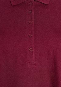 Bordeaux polo shirt met een gestructureerde brei, voorzien van een kraag en zes bijpassende met stof bedekte knopen langs de sluiting.