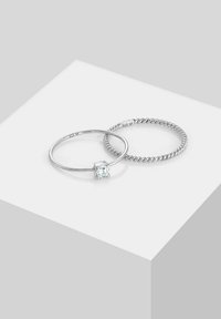 Sono mostrati due anelli in argento. Uno presenta una montatura con pietra preziosa trasparente; l'altro ha un design con fascia attorcigliata. Entrambi sono in argento sterling 925.