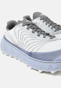 Zapatillas de correr grises y blancas con una parte superior texturizada con patrones ondulados, suela acolchada de color azul claro y cordones grises.