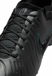 Scarpa da calcio nera con un upper in pelle texturizzata, lacci neri e un accento lucido del logo Nike con dettagli a motivo sul lato.