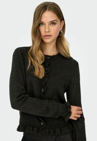 Cardigan noir en matériau tricoté doux, avec un devant à volants, des fermetures à boutons et des poignets et un ourlet en côtes.