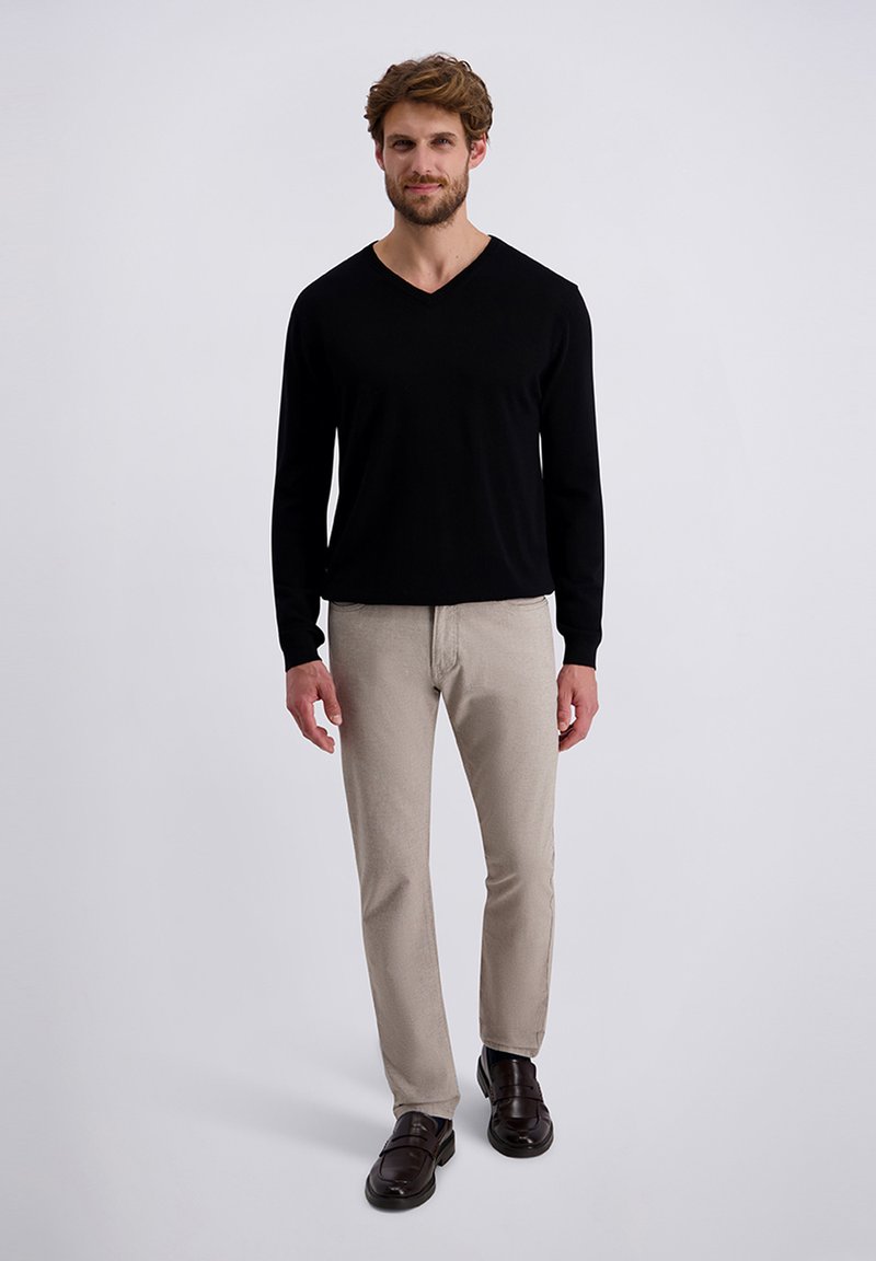 Schwarzes Langarm-V-Ausschnitt-Shirt kombiniert mit hellbeigen Hosen und dunkelbraunen Schuhen. Schlichtes Design, glatte Textur und neutrale Farben.