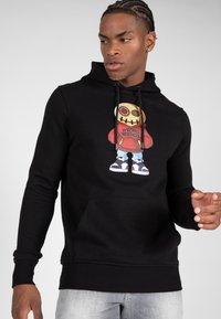 Zwarte hoodie met een grafisch ontwerp van een karakter met een gestikte mond en een oversized hoofd, gemarkeerde tekst "WRONG FRIENDS," ribbelboorden en -zoom.